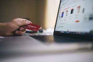 Man Holding A Credit Card Over A Laptop.