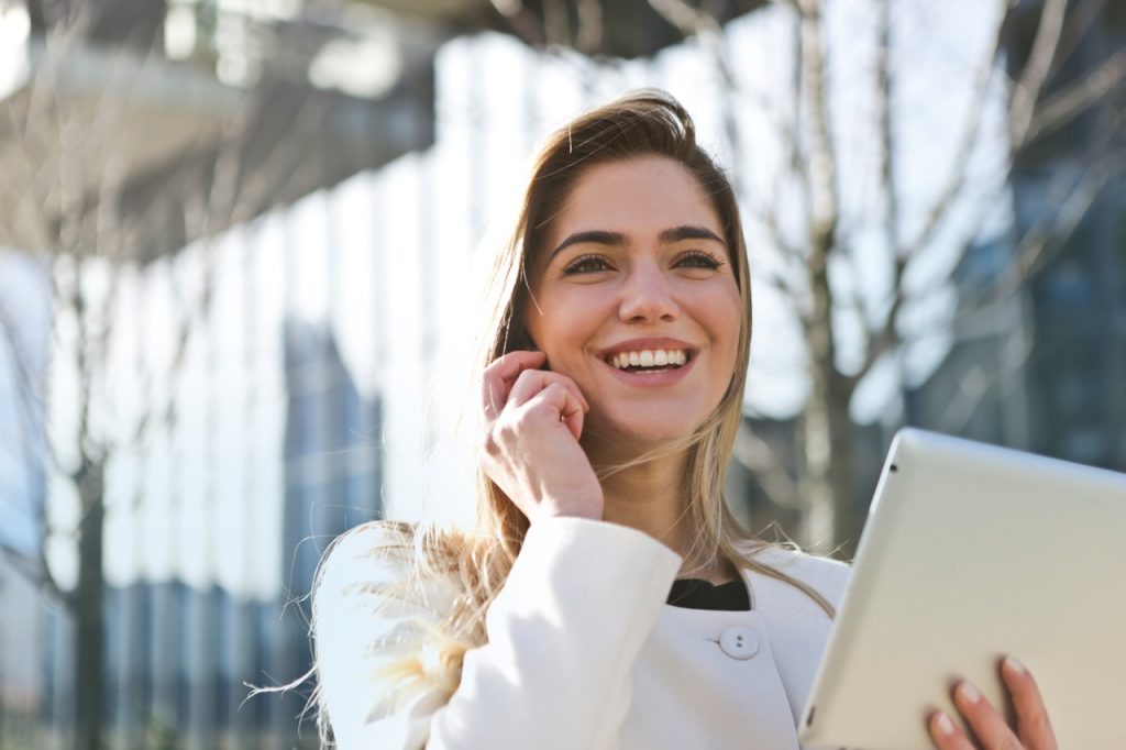 Woman talking on a cell phone while holding a laptop
